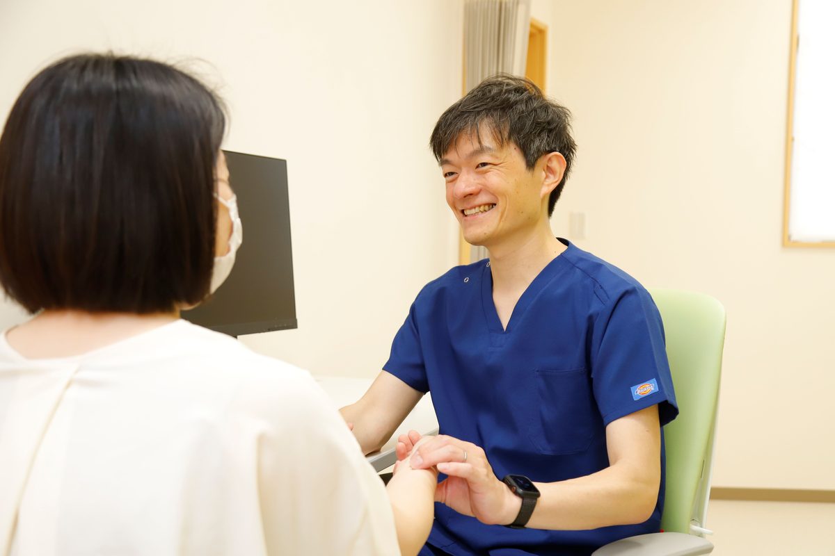 診察室で患者さんと笑顔で話す院長